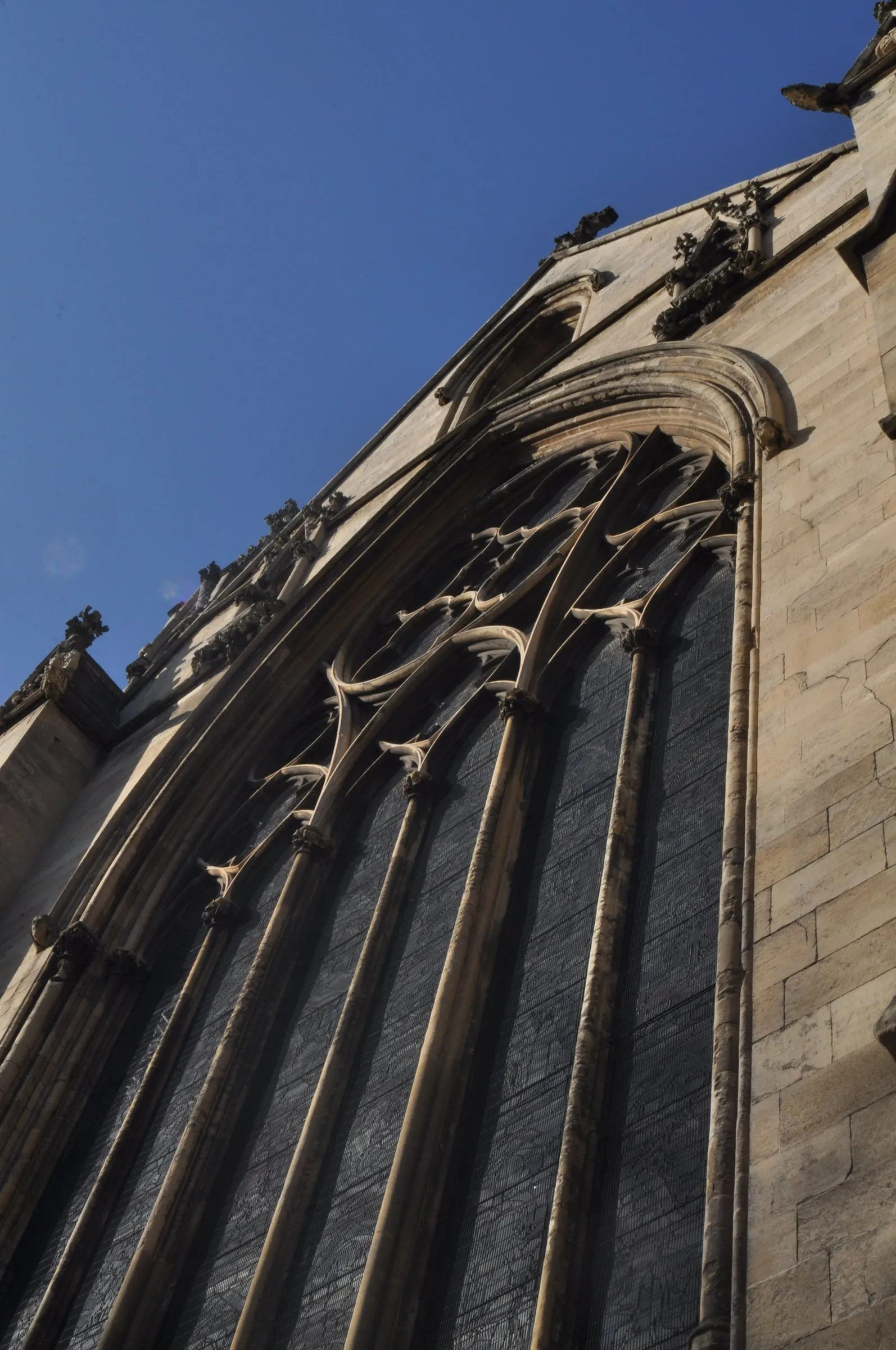 Carved Gothic church window against a blue sky.
