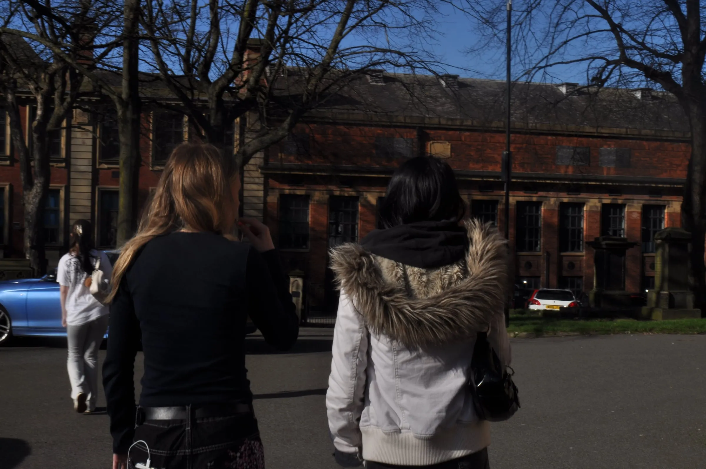 Two people walking across a town square.